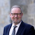 Image of Board Member Alasdair Hay standing outside of an office building.