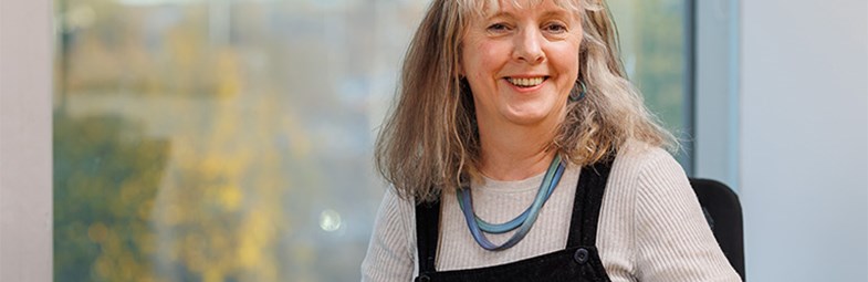 Image of Board Member Catriona Stewart sitting at a desk inside an office building.